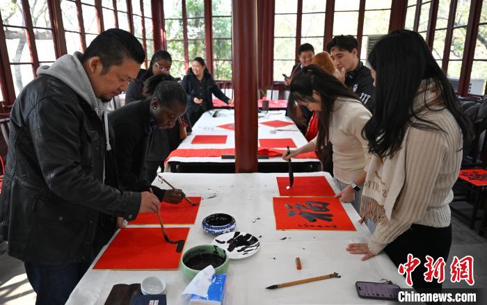 1月20日，多名外籍留学生等在西泠印社体验写福。当日，来自巴西、马来西亚、加纳、哈萨克斯坦的外籍留学生在浙江杭州西泠印社体验福贴、春联和篆刻，感受古老的中国传统文化。中新社记者 王刚 摄